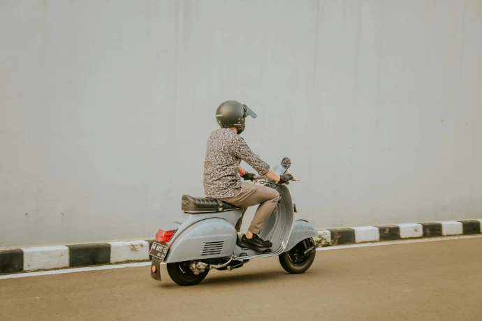 man in brown and white checkered dress shirt riding on gray motor scooter